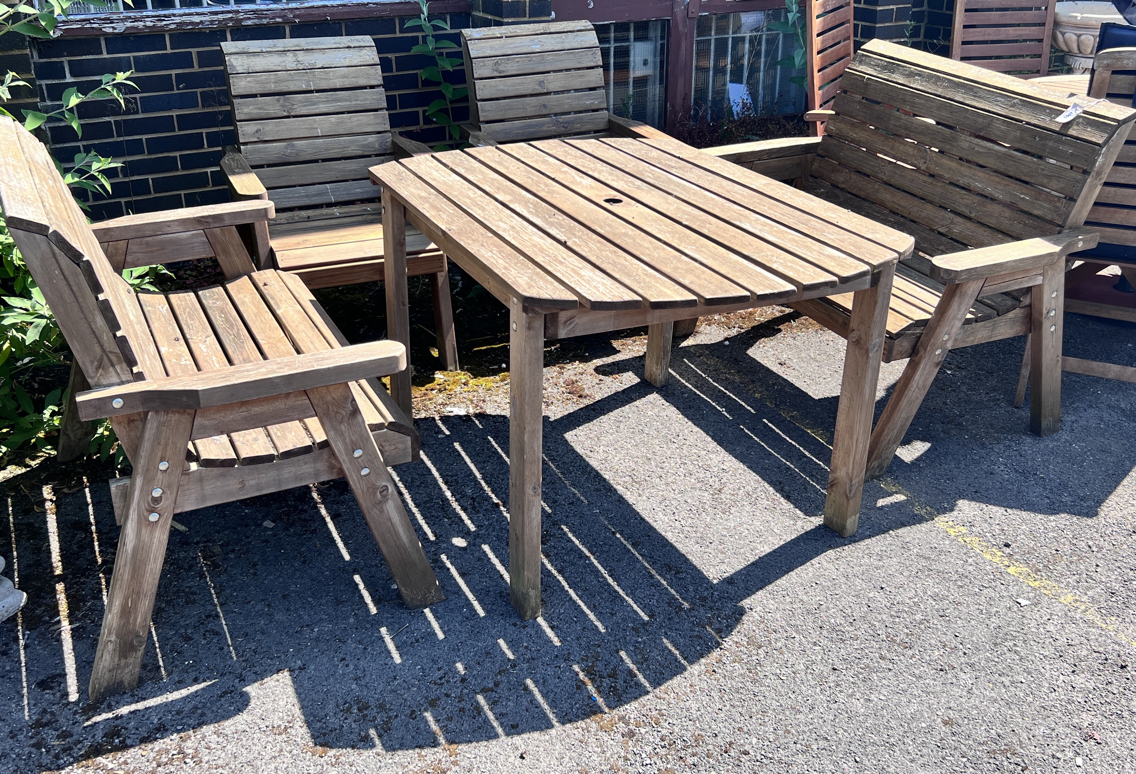 A rectangular slatted teak garden table, length 130cm, width 96cm, height 79cm, together with a pair of armchairs and a pair of benches